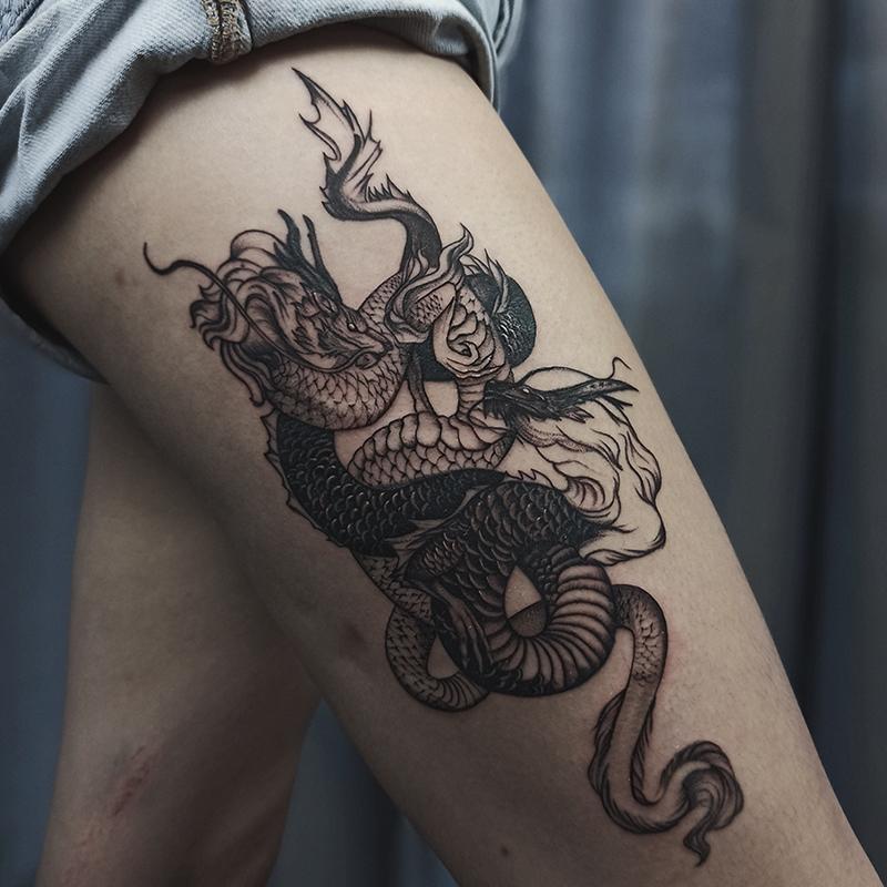 Противостояние Инь и Янь в виде графических драконов на бедре